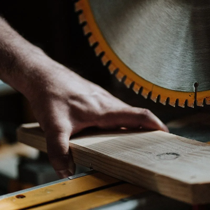 Carpintero cortando una tabla de madera con sierra circular