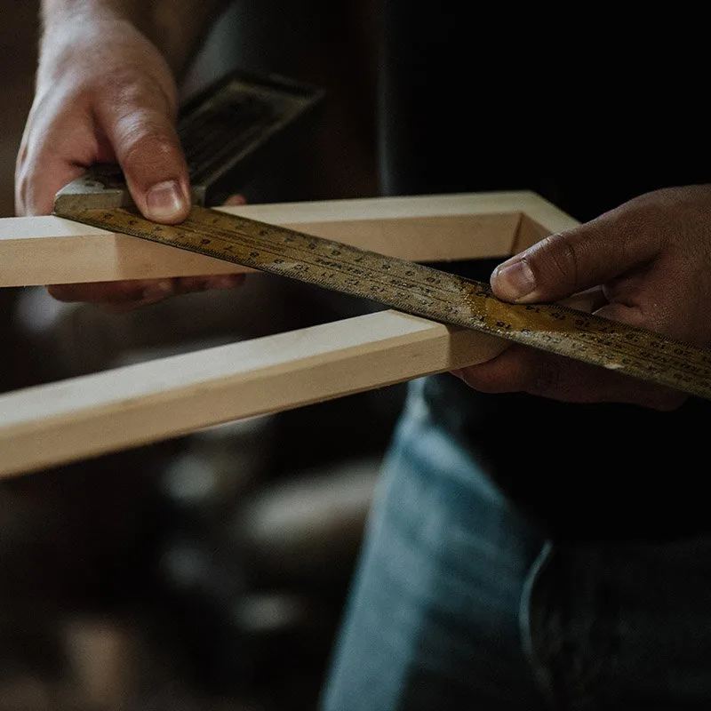 Carpintero midiendo un marco de madera con escuadra