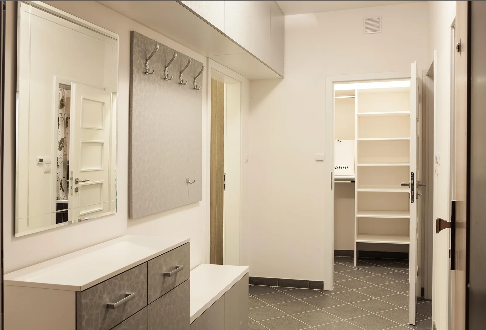 Built-in closet with open shelving, mirror and coat hooks in a hallway