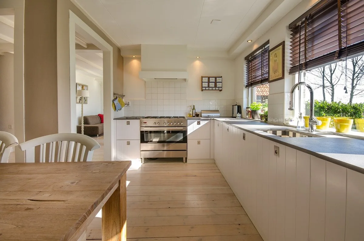 Cocina luminosa con gabinetes blancos y piso de madera